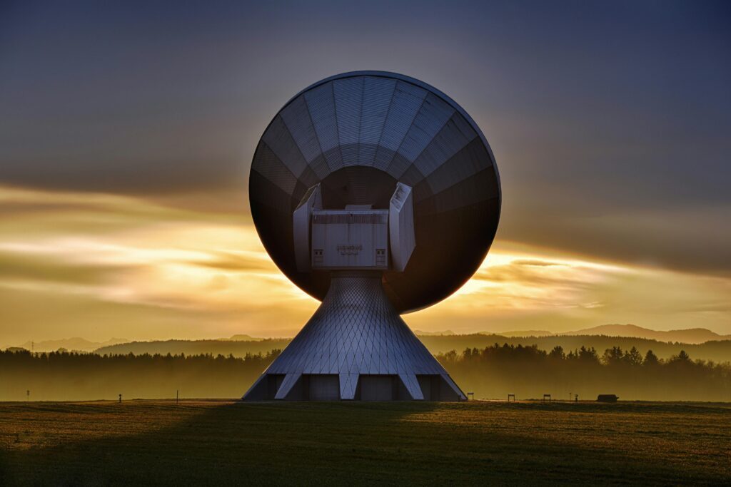 Large satellite dish communication tower in a field at sunrise, symbolizing advanced technology used by digital marketing services near me to enhance business connectivity and growth